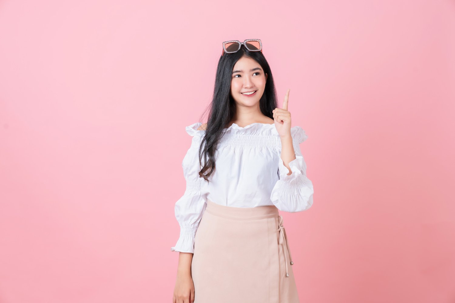 Smiling Asian Woman Stand and Pointing Finger on Pink Background.